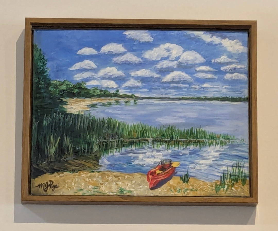 Painting of a lake scene with a red boat on a sandy shore, framed in brown.