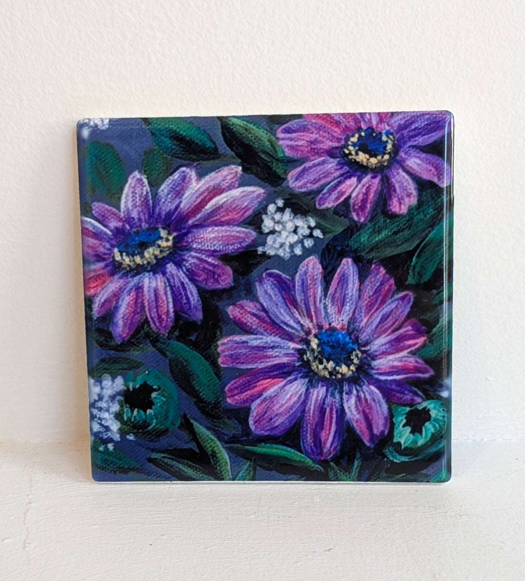 Square tile with a floral design featuring purple flowers.