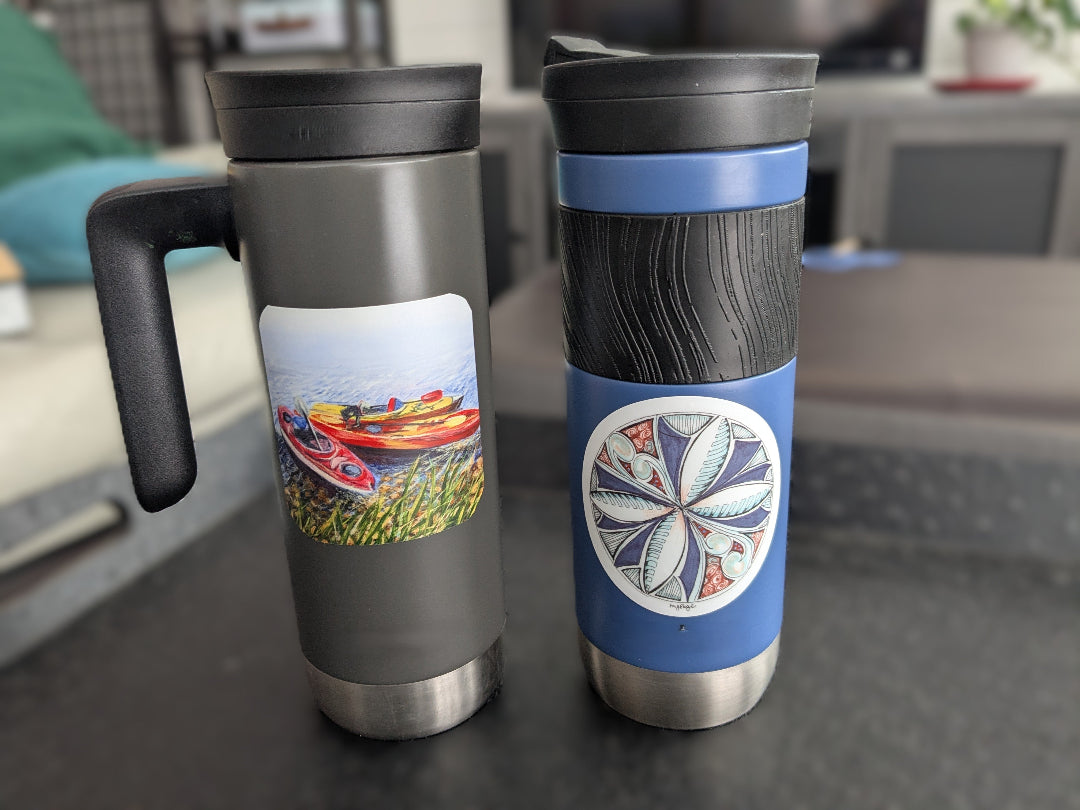 Two travel mugs with different designs on a surface.