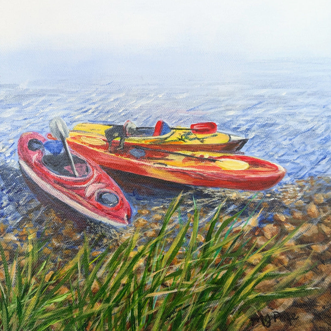 Three kayaks on a pebbly shore with grass, one red and one yellow, on a water background.