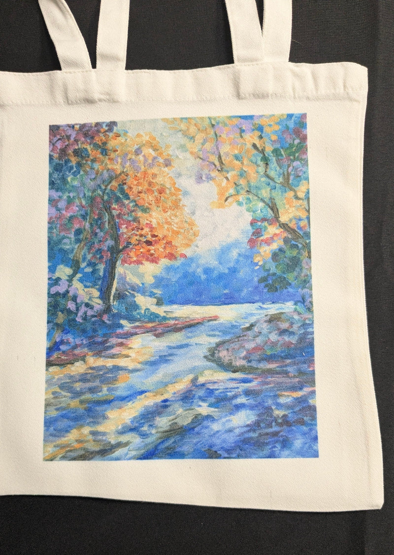 Tote bag with a colorful landscape design of a path and trees.